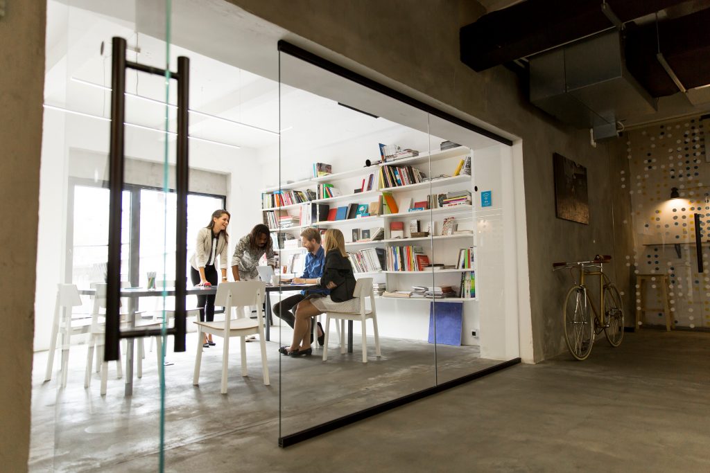 A group of working professionals meet in a conference room to discuss their grant strategy.