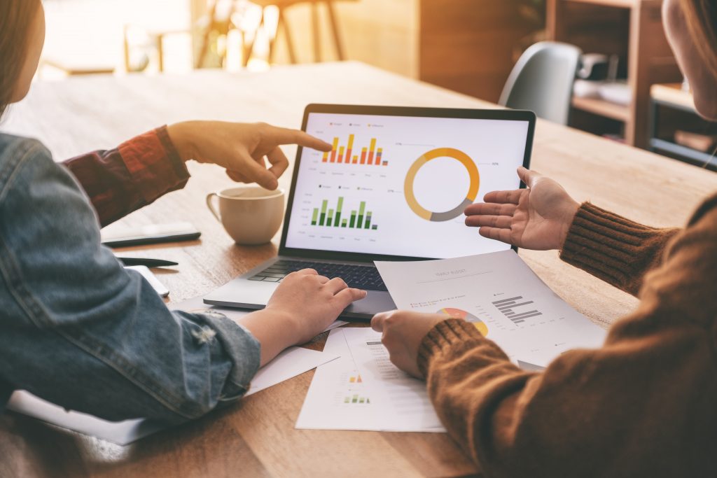 A team of nonprofit professionals review their organization's financial performance using a dashboard displaying charts on a laptop.